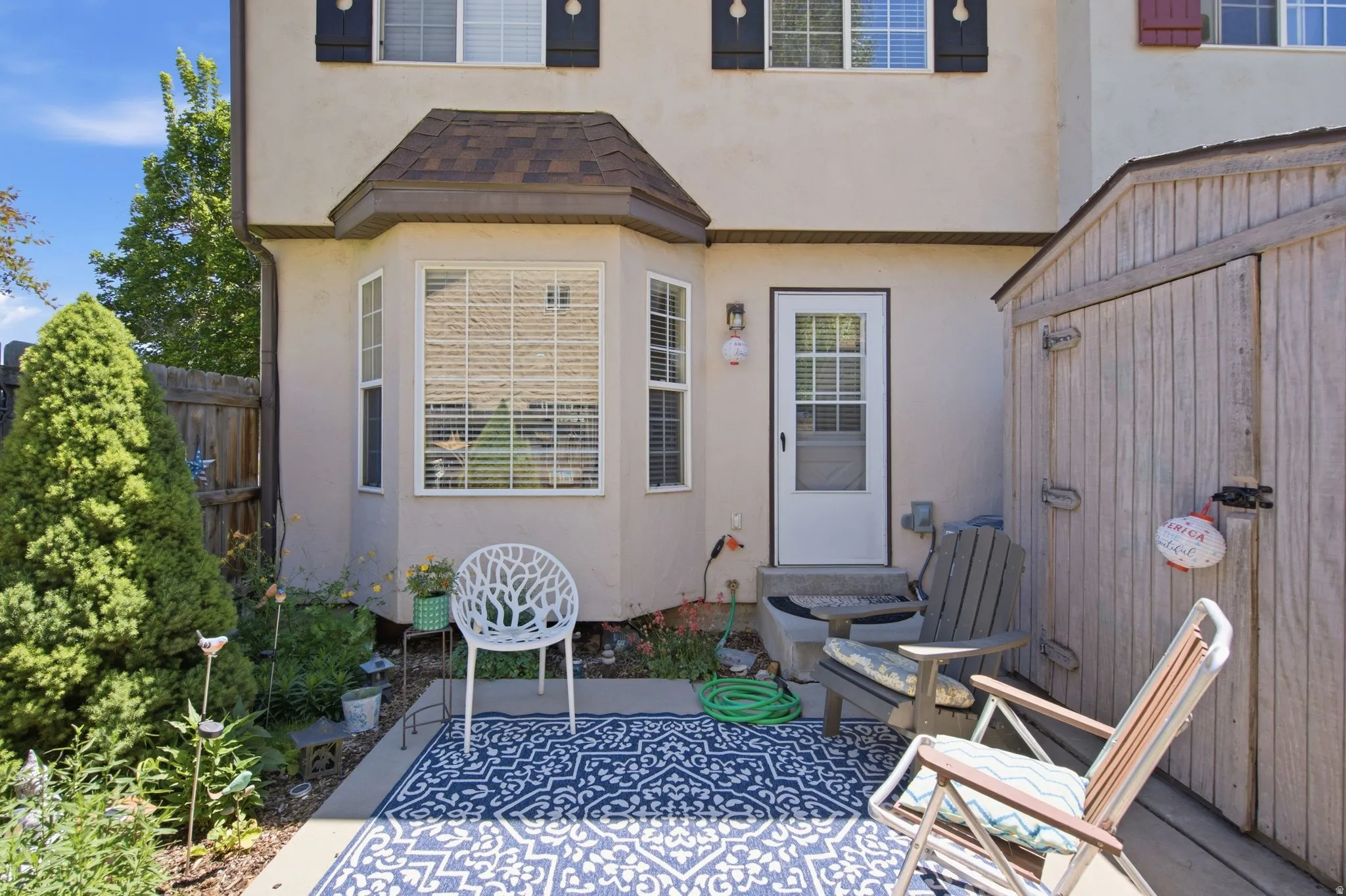 Private patio area featuring a bay window, stucco exterior, and a wood storage shed