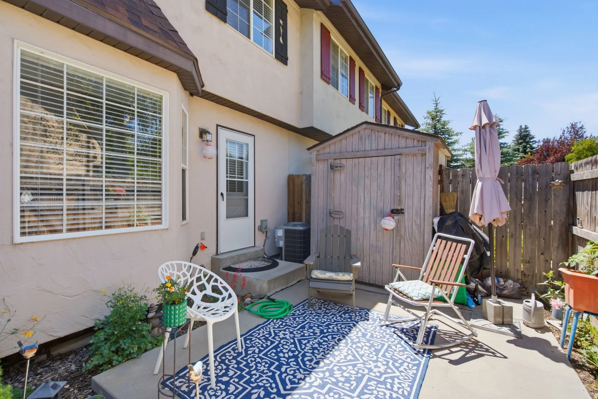 Concrete patio with a wood storage shed, fenced perimeter, and exterior building access