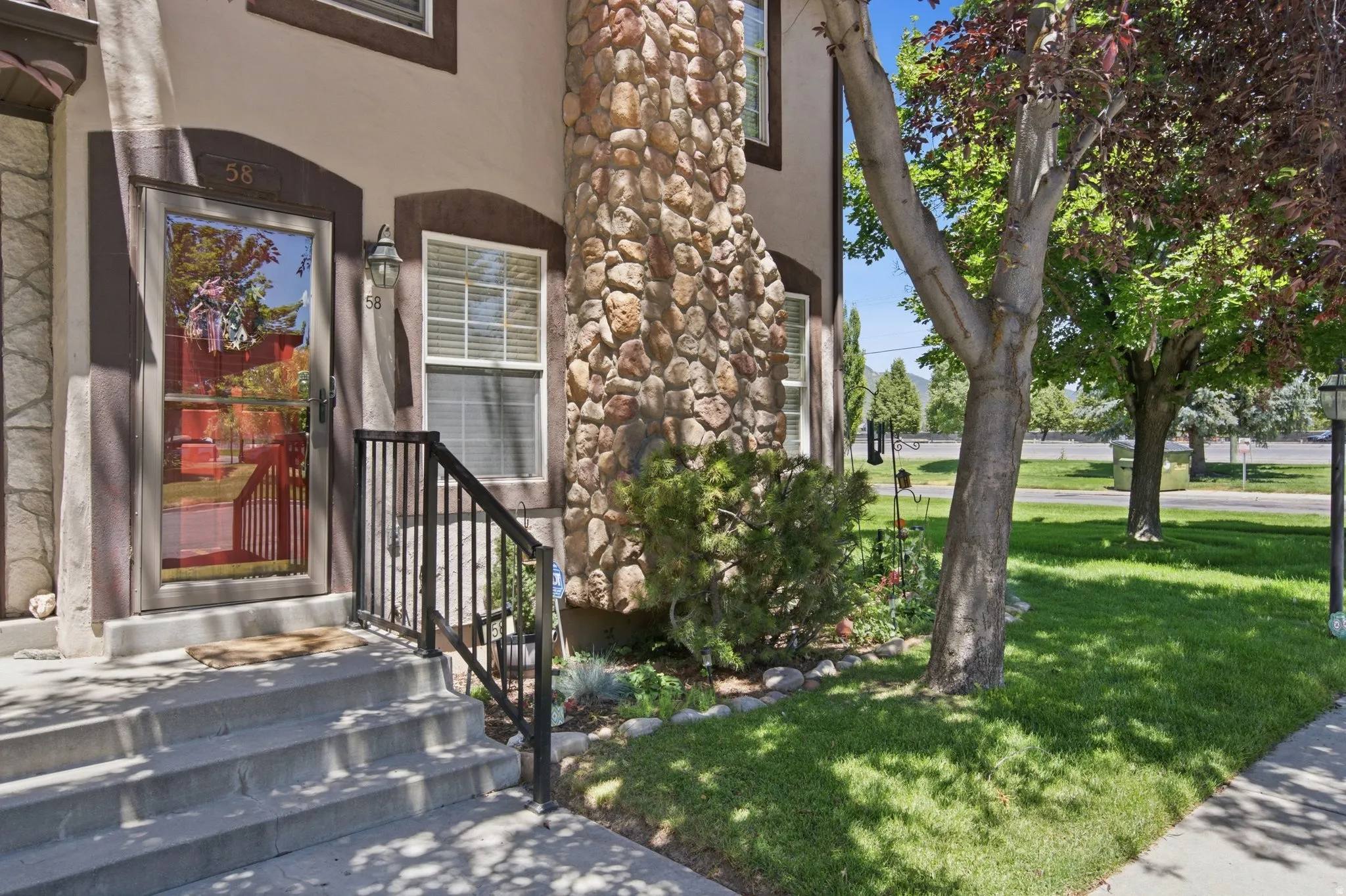 Stucco exterior featuring a prominent stone facade element and concrete entry steps