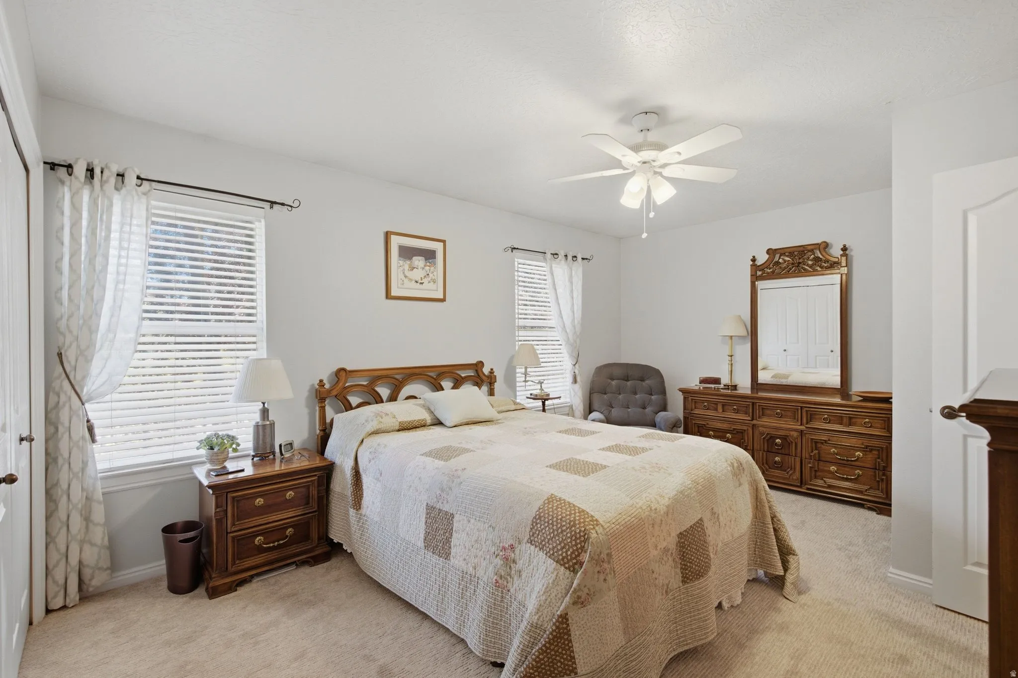 Carpeted bedroom with two windows featuring blinds and drapes