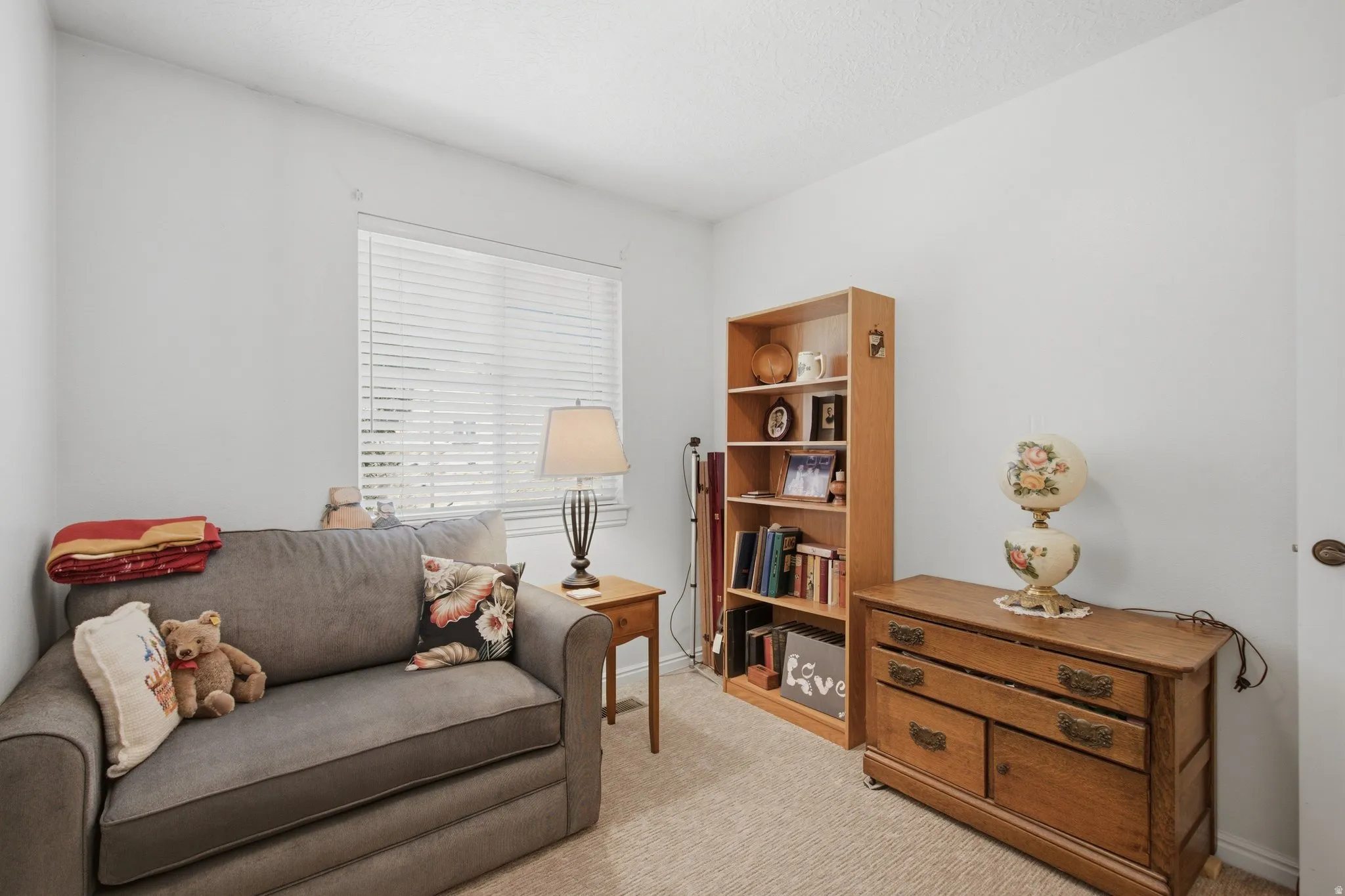 Bright room featuring a single window with horizontal blinds, light-colored walls, and carpet flooring