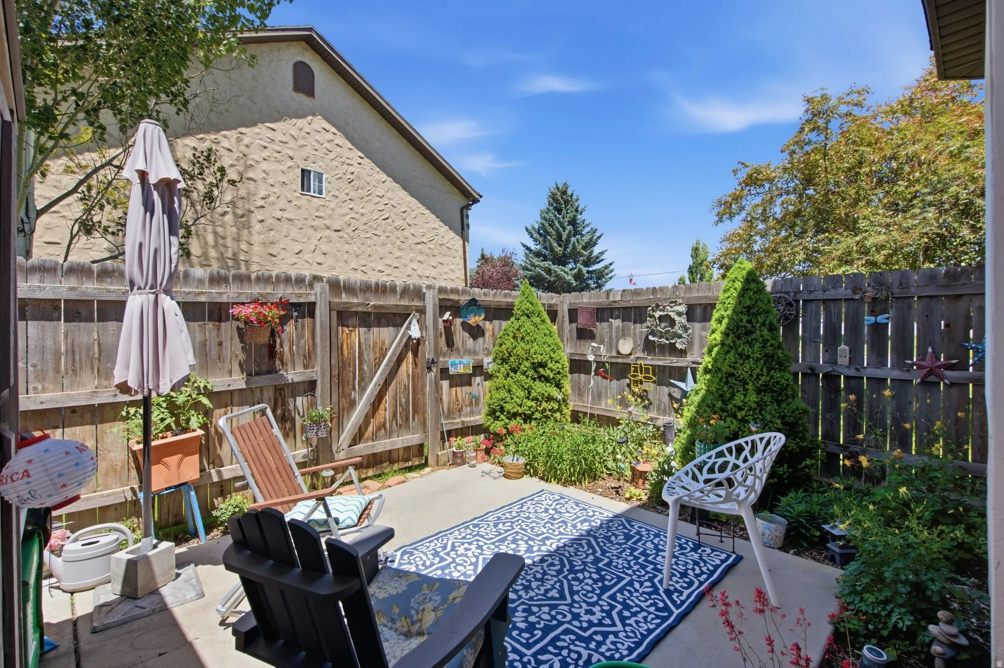 Private patio space featuring a solid wood fence, established plantings, and concrete paving