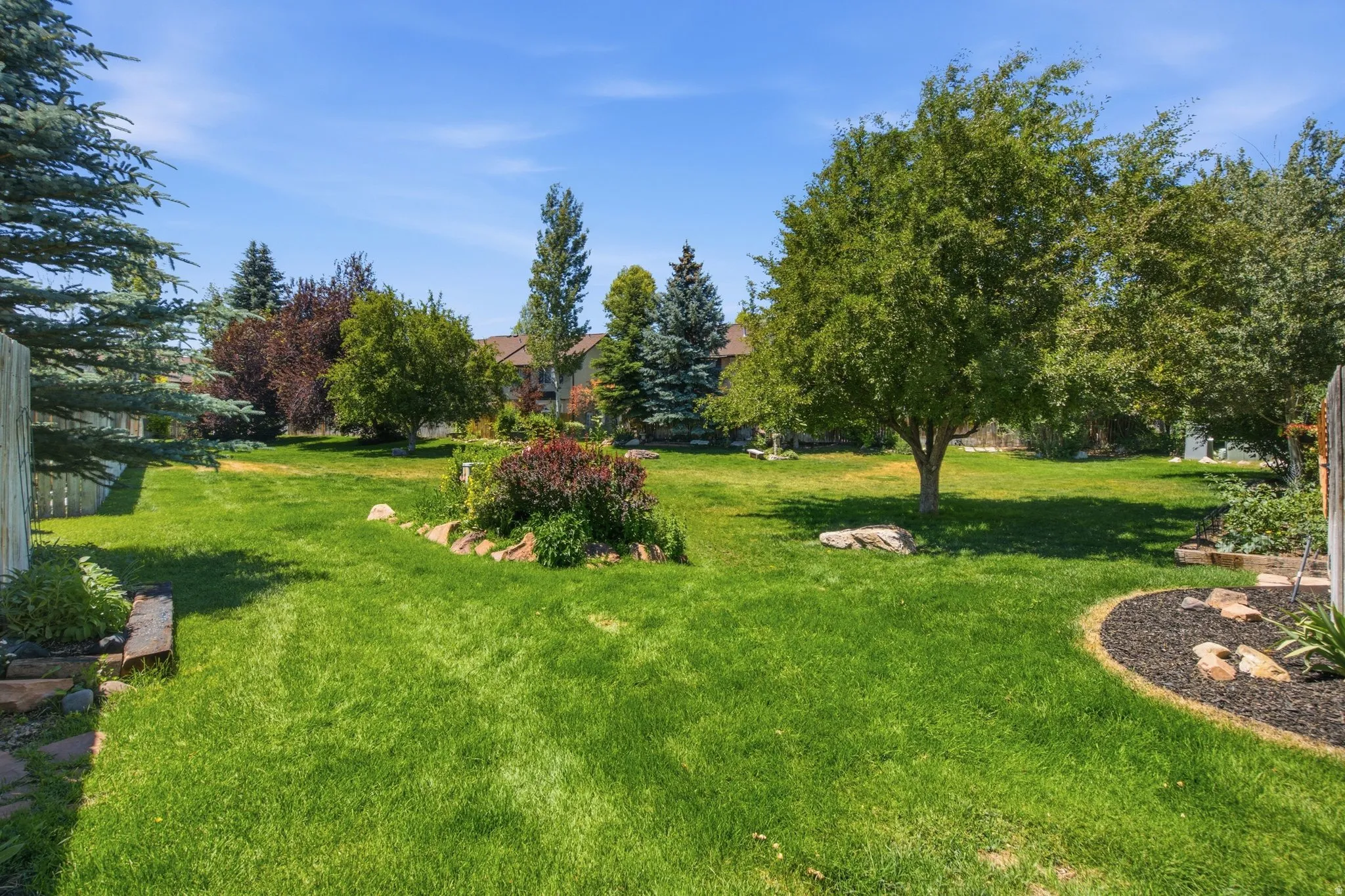 Expansive green lawn with mature trees and established garden beds