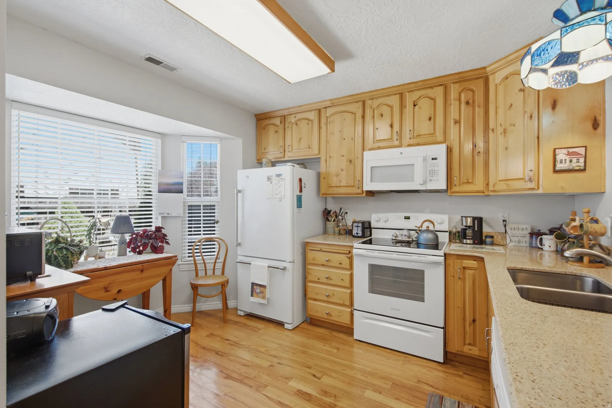 Kitchen featuring natural wood cabinetry, wood-finish flooring, and light-toned countertops