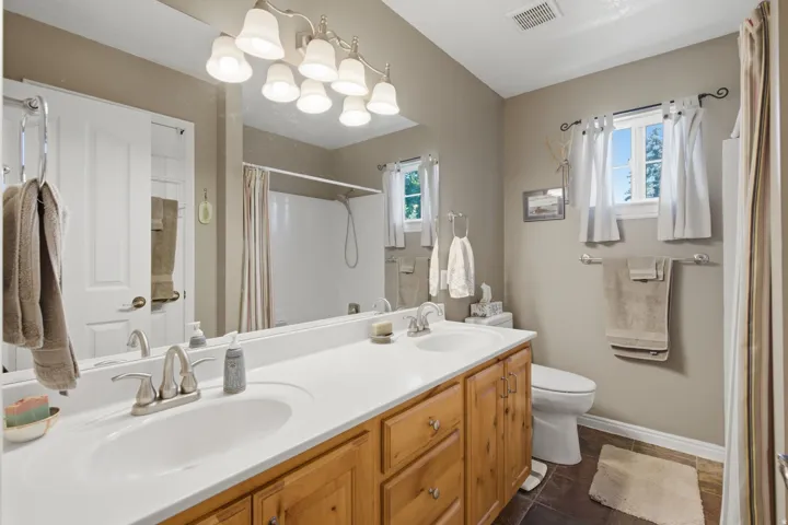 Double vanity with white integrated sinks, light wood-finish cabinetry, and brushed nickel fixtures