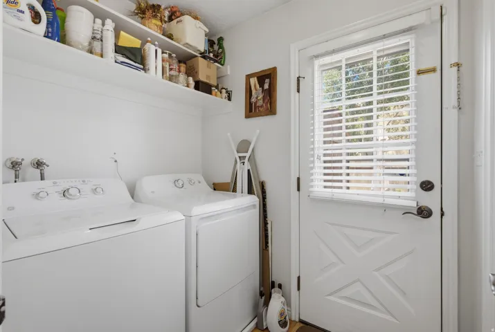 Dedicated laundry area featuring a white door with window and blinds, white walls, and built-in shelving