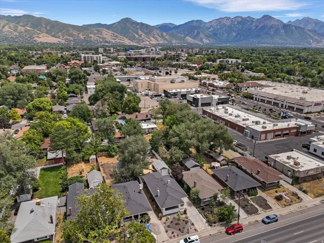 Residential area surrounded by mature trees, with commercial buildings and a mountain range in the background