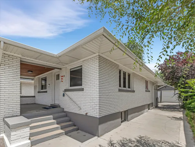 White brick exterior with a covered porch featuring a wood-panel ceiling and recessed lighting