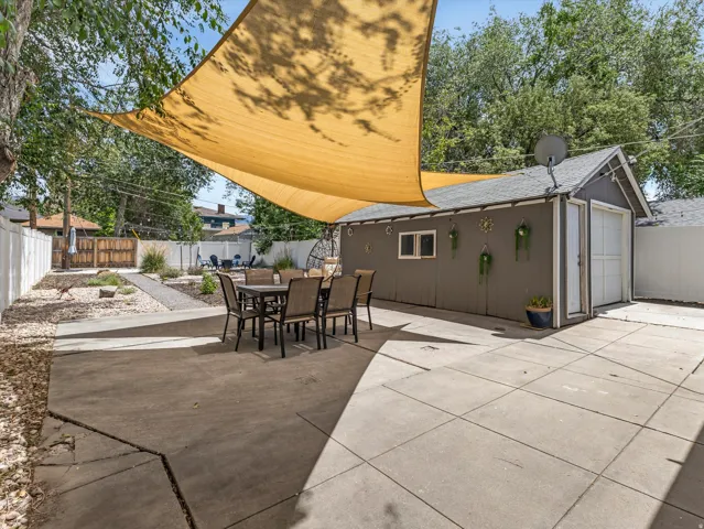 Backyard featuring concrete patio, shade sail, detached garage, and perimeter fencing