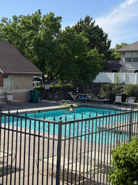 Fenced outdoor swimming pool with surrounding concrete patio and landscaping