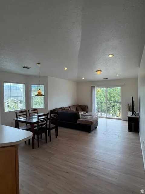 Open-concept living area with new LVP flooring, recessed lighting, and a sliding glass door leading to an exterior balcony