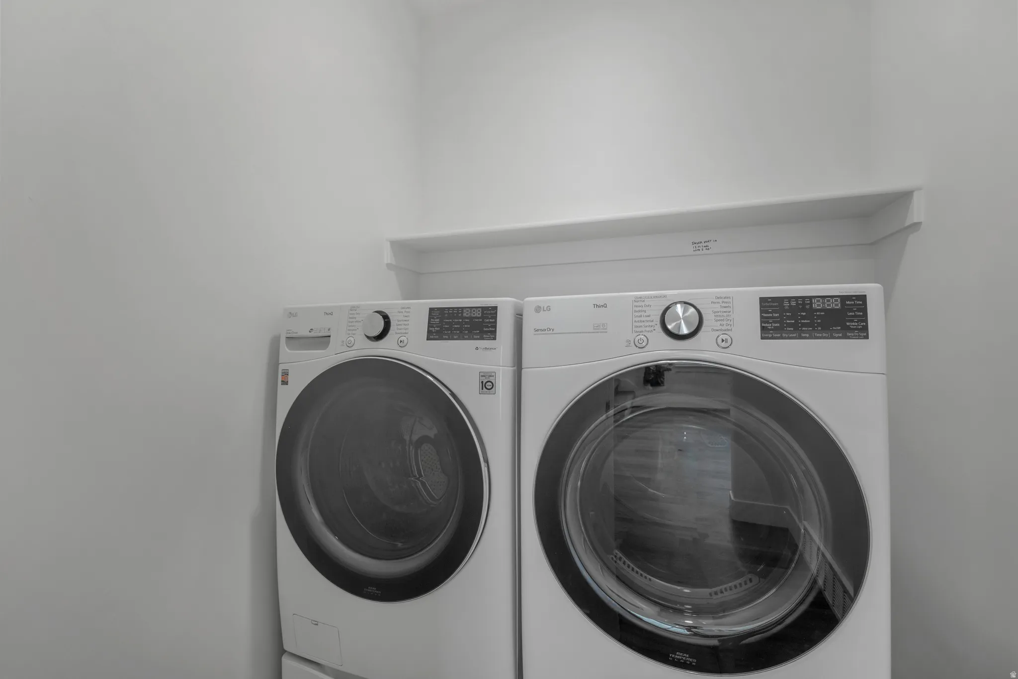 Dedicated laundry area featuring a white shelf and bright walls