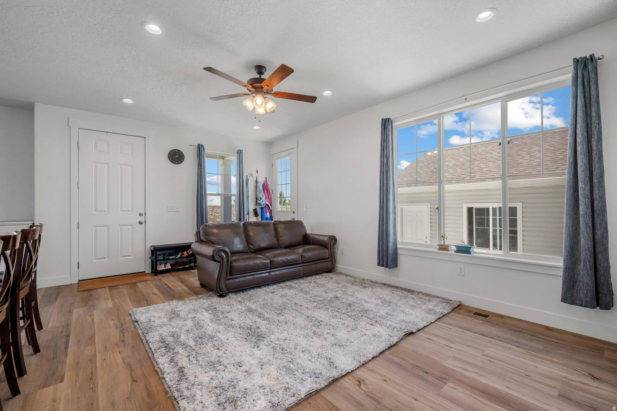 Spacious living area featuring wood-finish flooring, recessed lighting, and a ceiling fan with integrated lighting