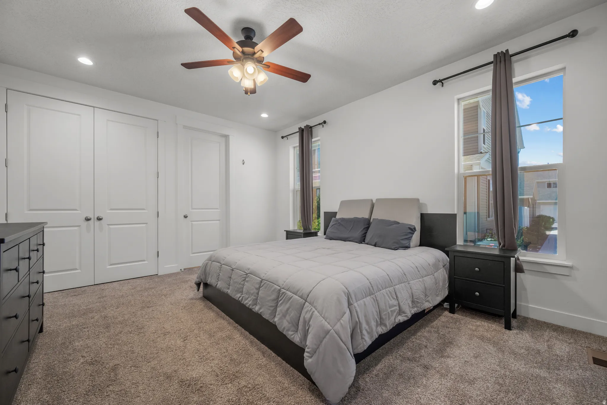 Carpeted room featuring a ceiling fan with integrated lighting, recessed lighting, and two windows with white trim