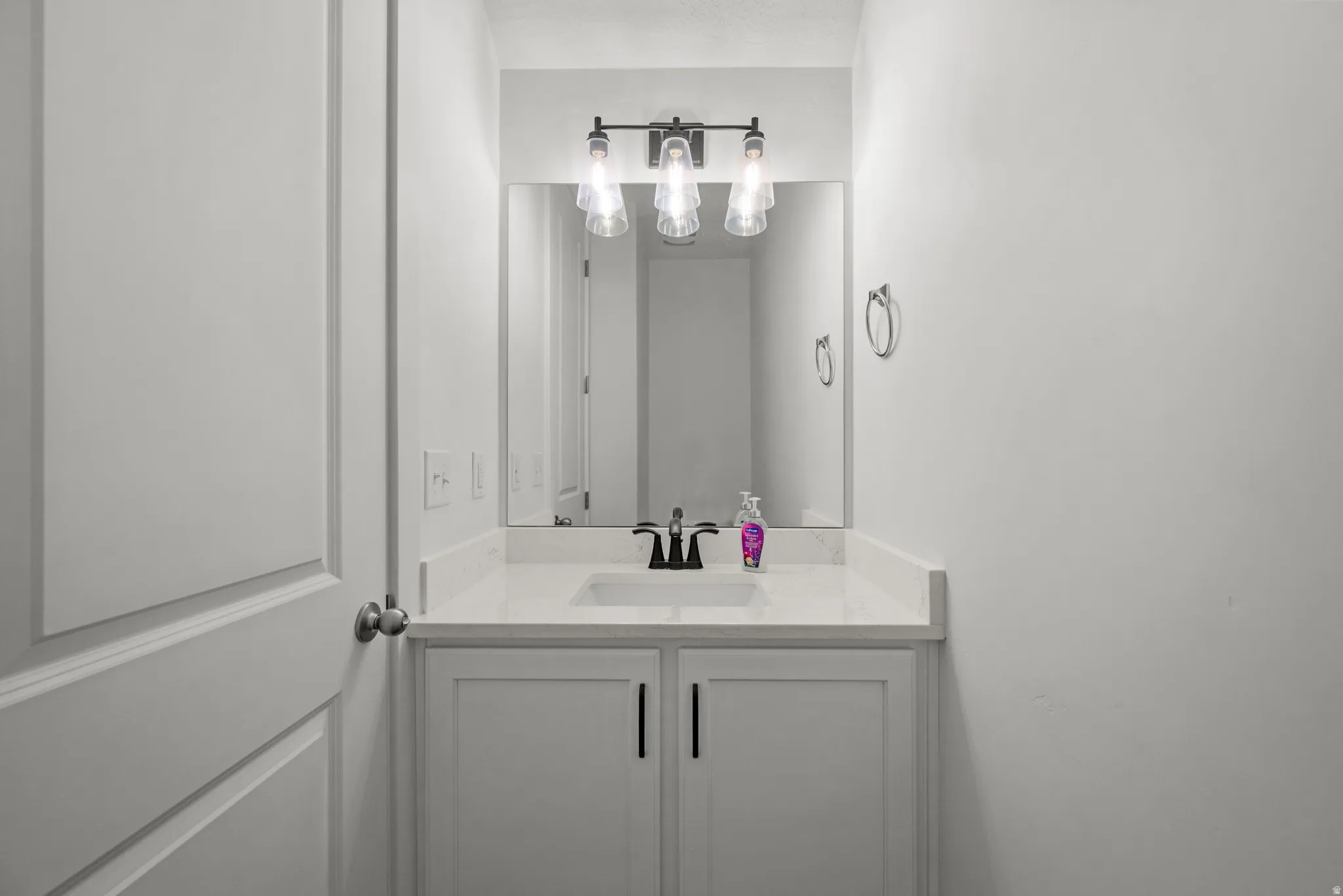 Single vanity featuring a white countertop, undermount sink, and black faucet