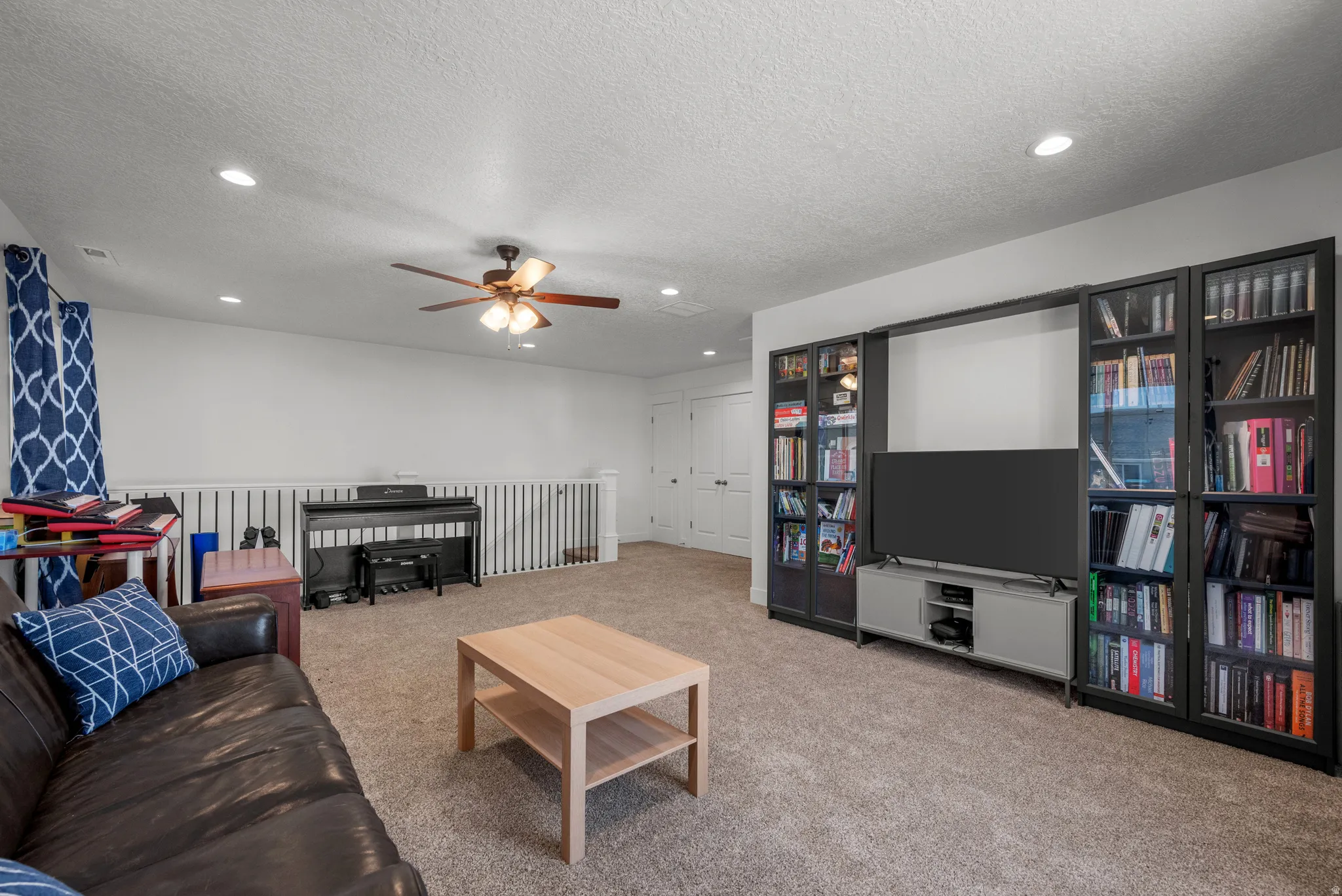 Spacious carpeted room featuring recessed lighting, a ceiling fan, and built-in shelving