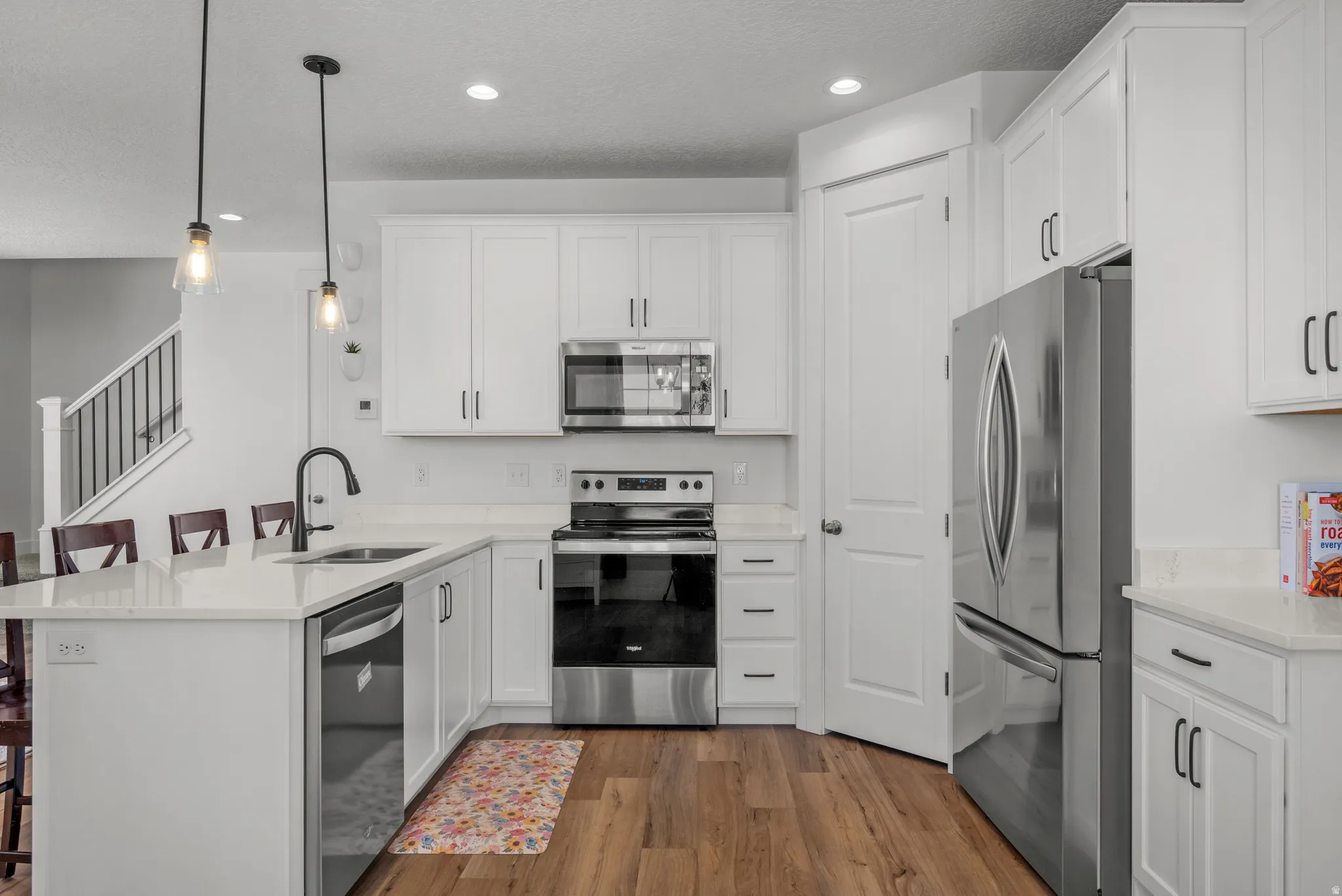 Bright kitchen featuring white shaker cabinetry, stainless steel appliances, and quartz countertops