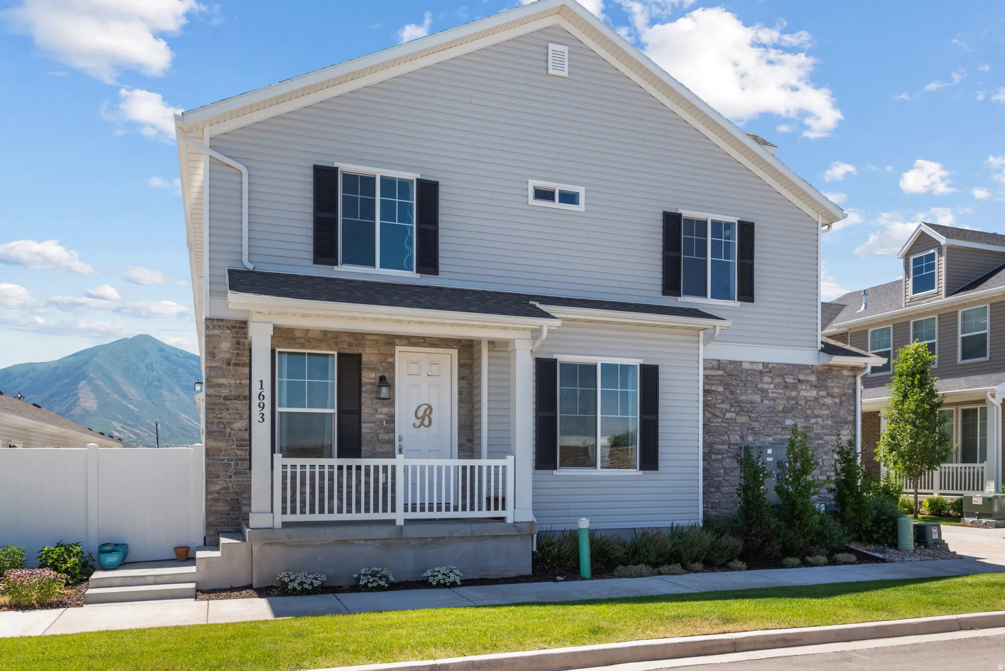Two-story residence featuring light gray siding and a partial stone facade