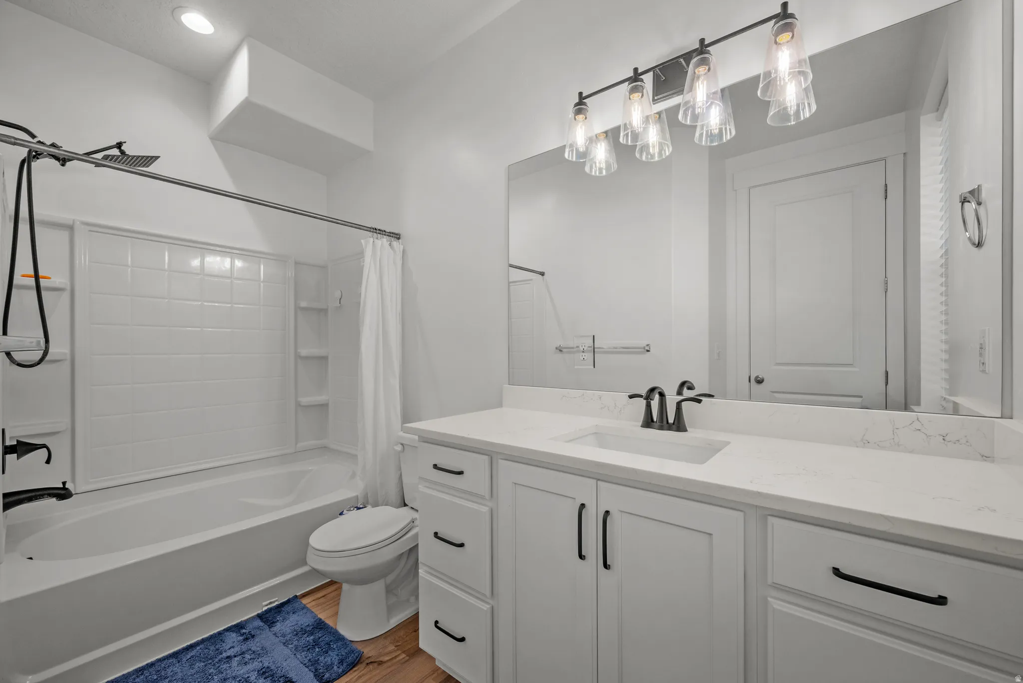 Bathroom featuring a white vanity with a light-colored countertop, an integrated sink with a dark-finished faucet, and a large wall-mounted mirror