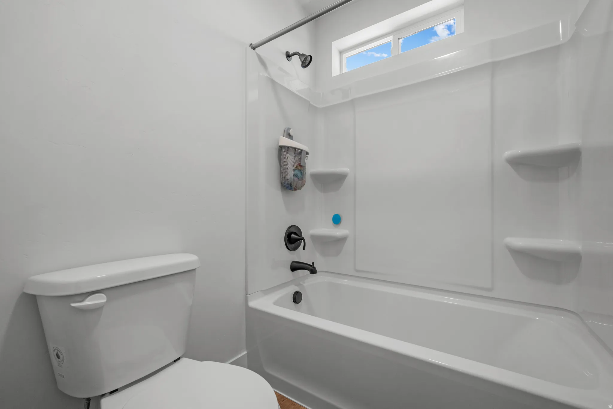 Full bathtub and shower combination with dark bronze fixtures and integrated shelving