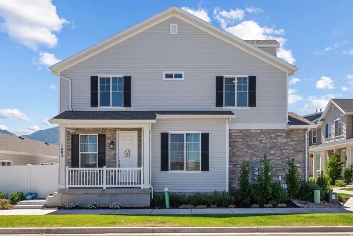 Two-story residence featuring light gray siding and a stone facade accent