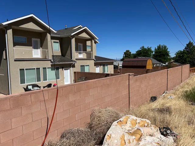 Stucco exterior with multiple windows and doors, featuring two upper-level balconies with modern railings