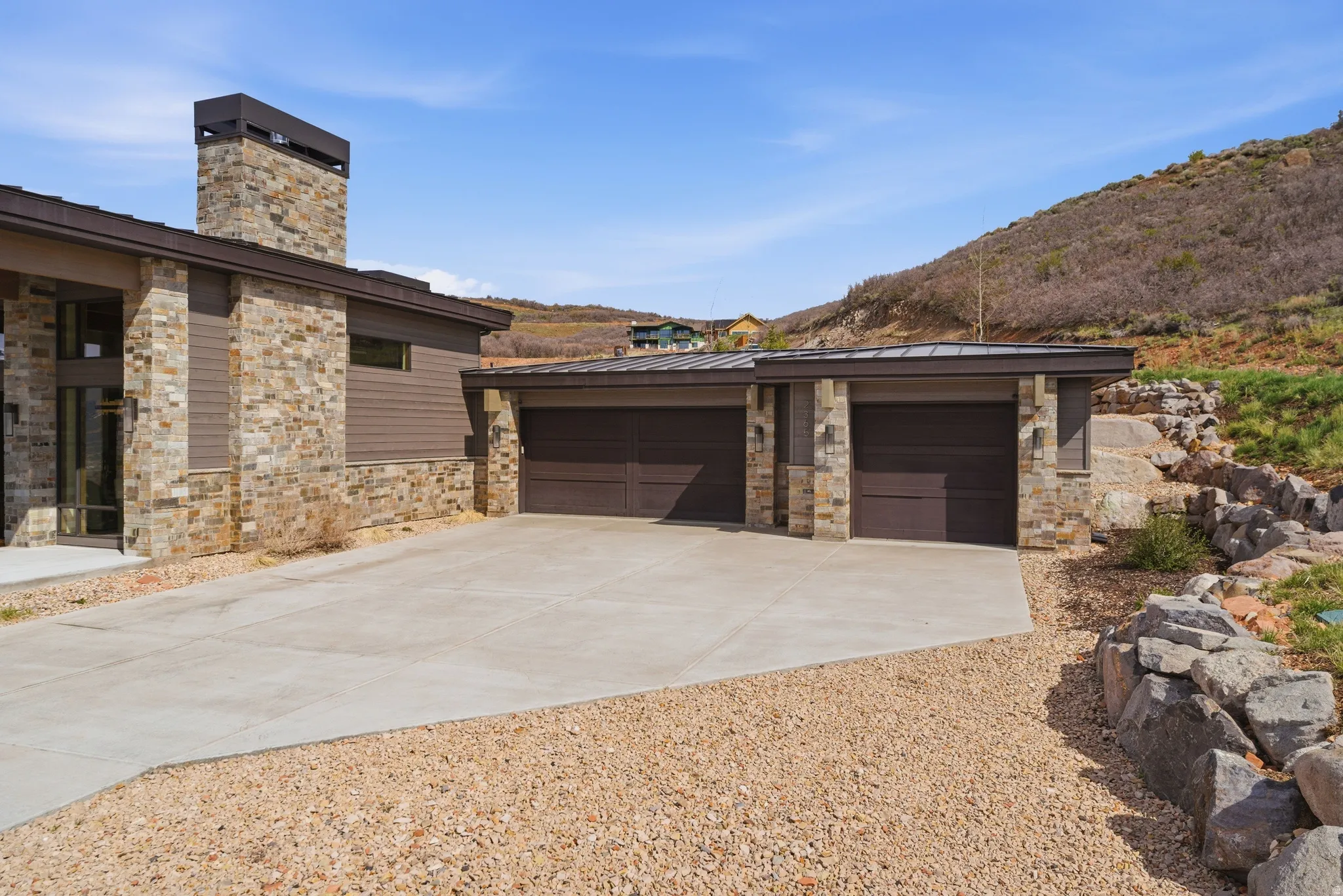 Contemporary exterior featuring natural stone accents, horizontal siding, and a two-car garage