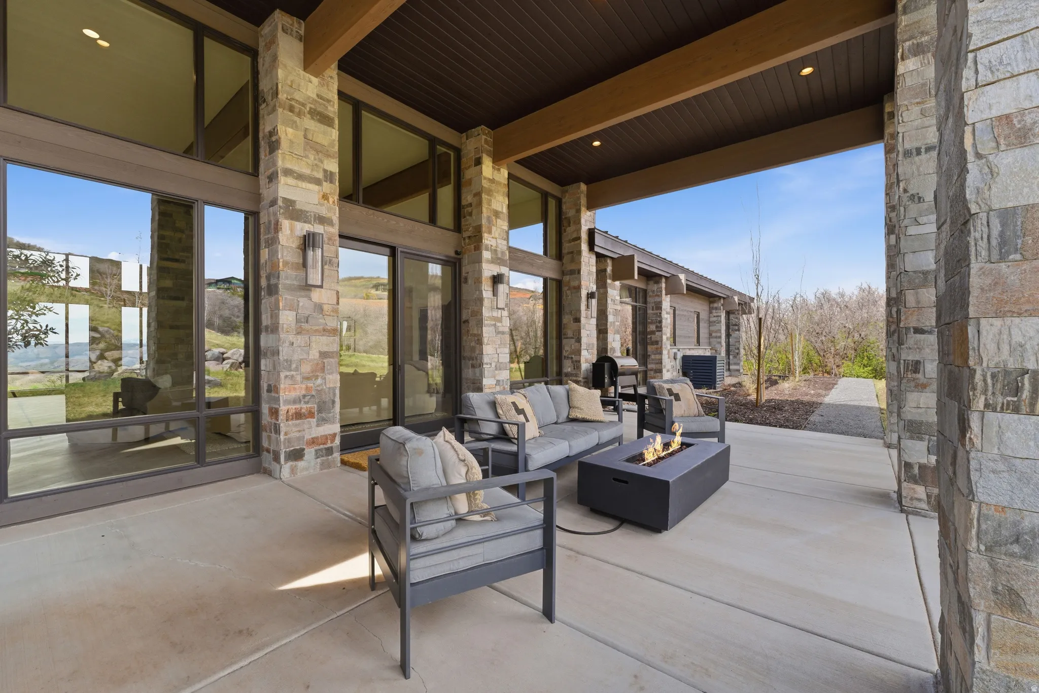 Covered patio with stone columns, a concrete surface, and recessed lighting