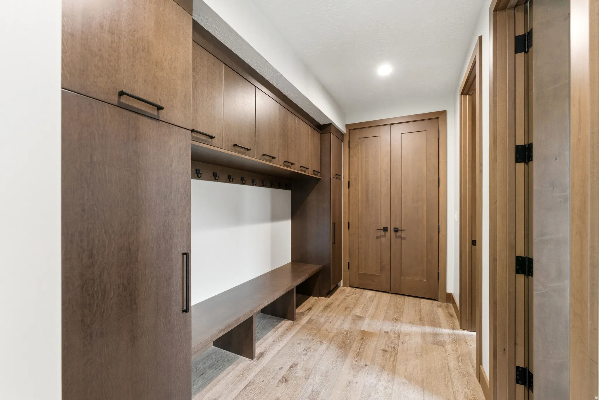 Integrated mudroom cabinetry featuring a built-in bench, upper storage, and wall hooks
