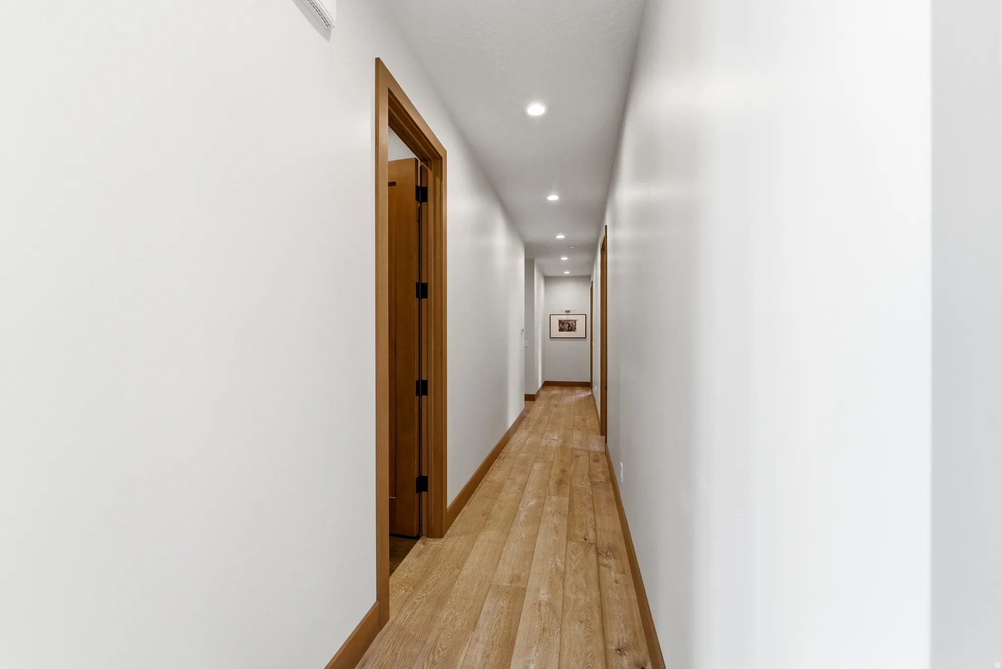 Hallway featuring wood-finish flooring, recessed lighting, and white walls