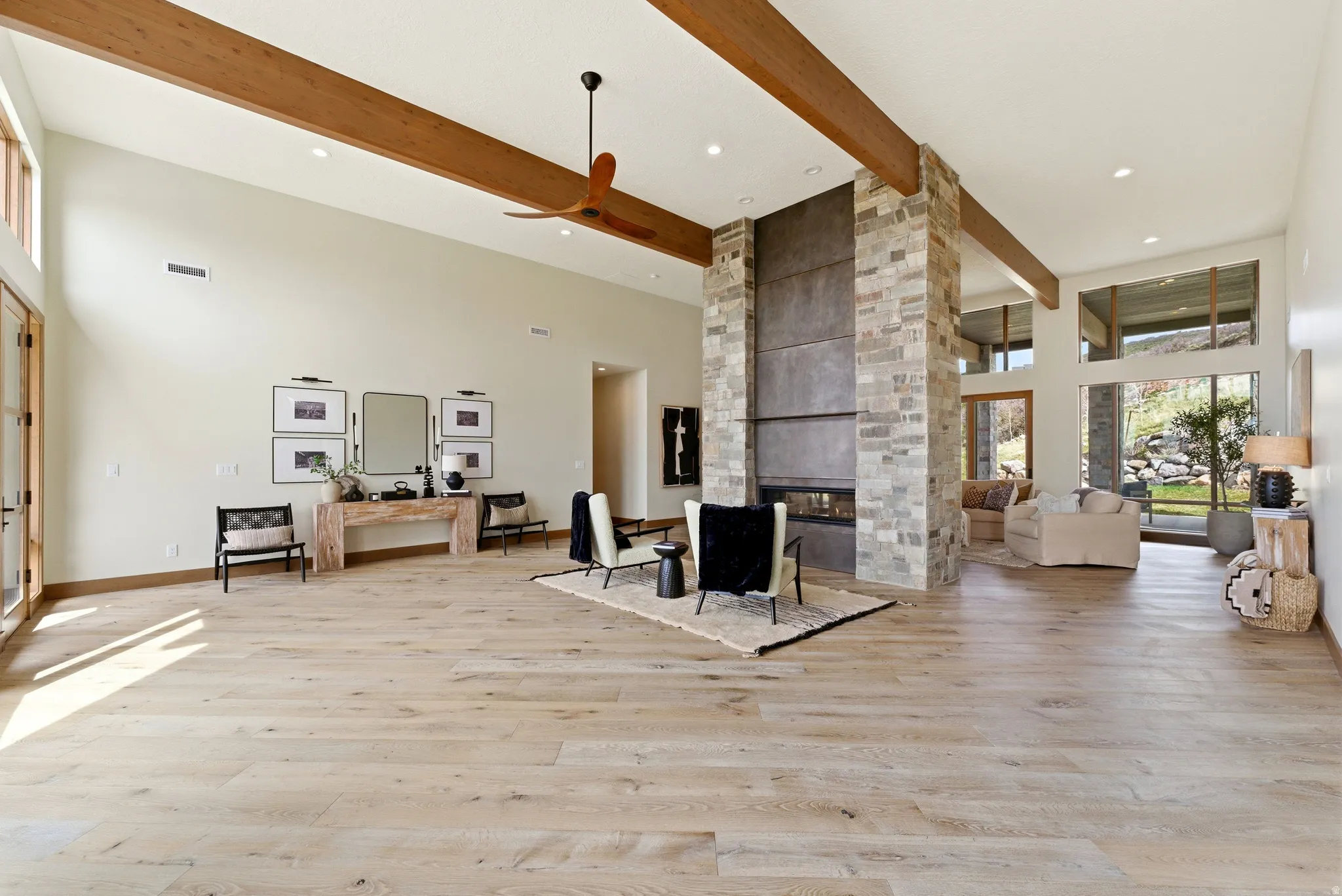 Spacious living area featuring light wood-finish flooring and high ceilings with exposed wood beams