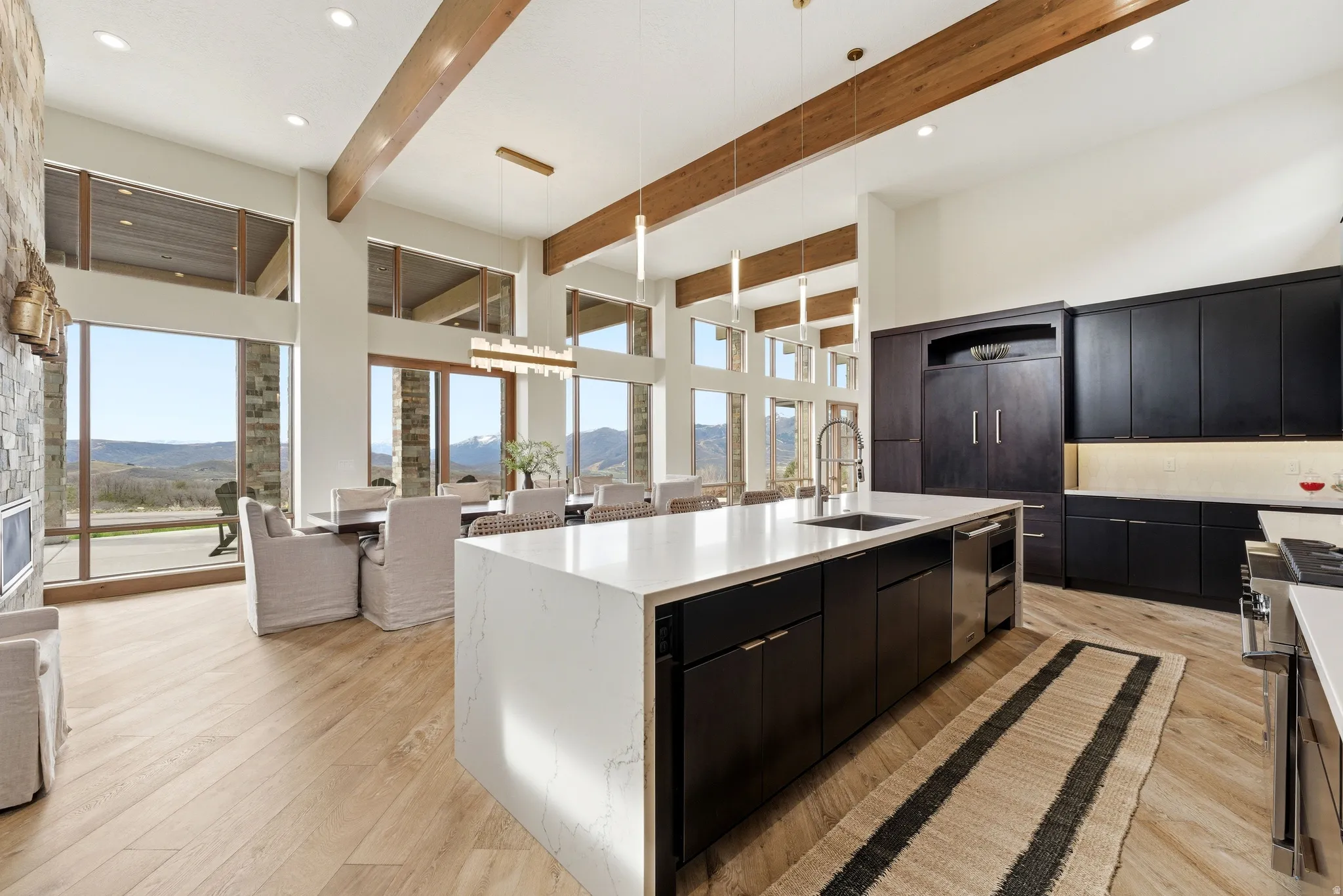 Spacious open-concept living area featuring a large center island with a waterfall countertop, integrated stainless steel appliances, and dark wood-finish cabinetry