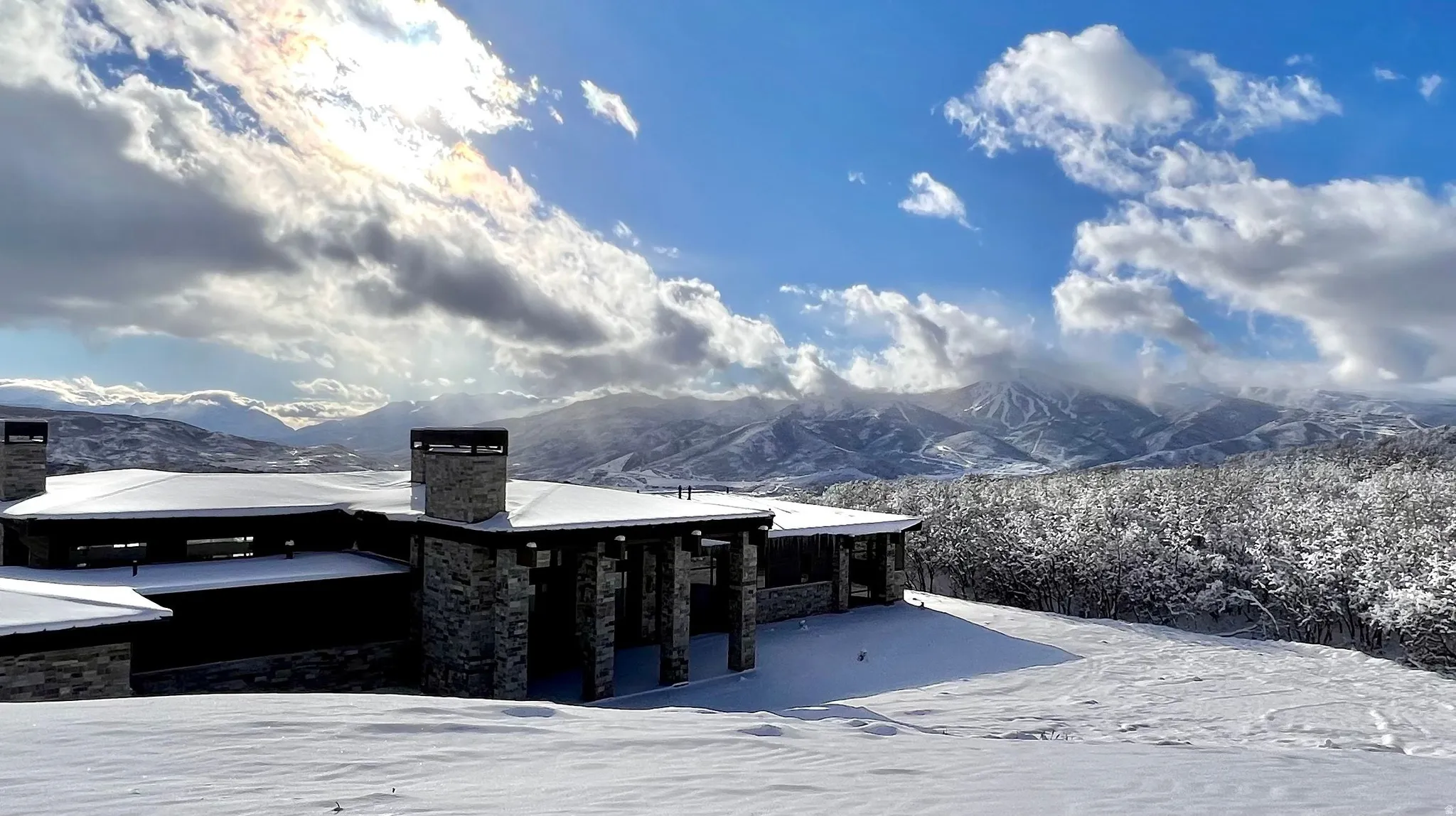 Stone facade residence with prominent chimneys and a deep overhang, situated on a snow-covered landscape