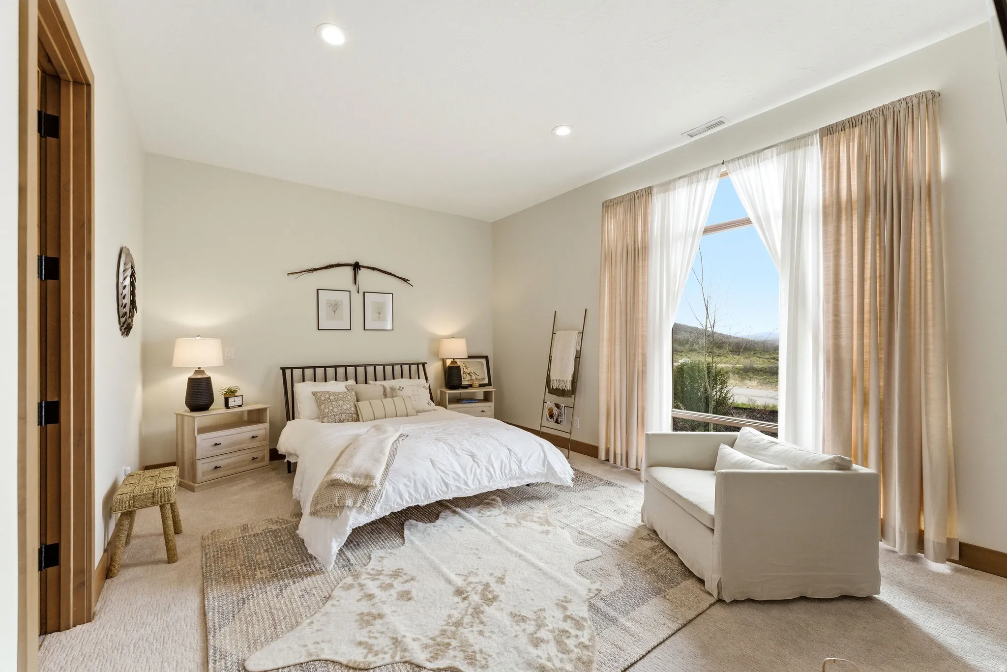 Bedroom featuring a large window, vaulted ceiling, recessed lighting, wood-finish door trim, and neutral carpeting