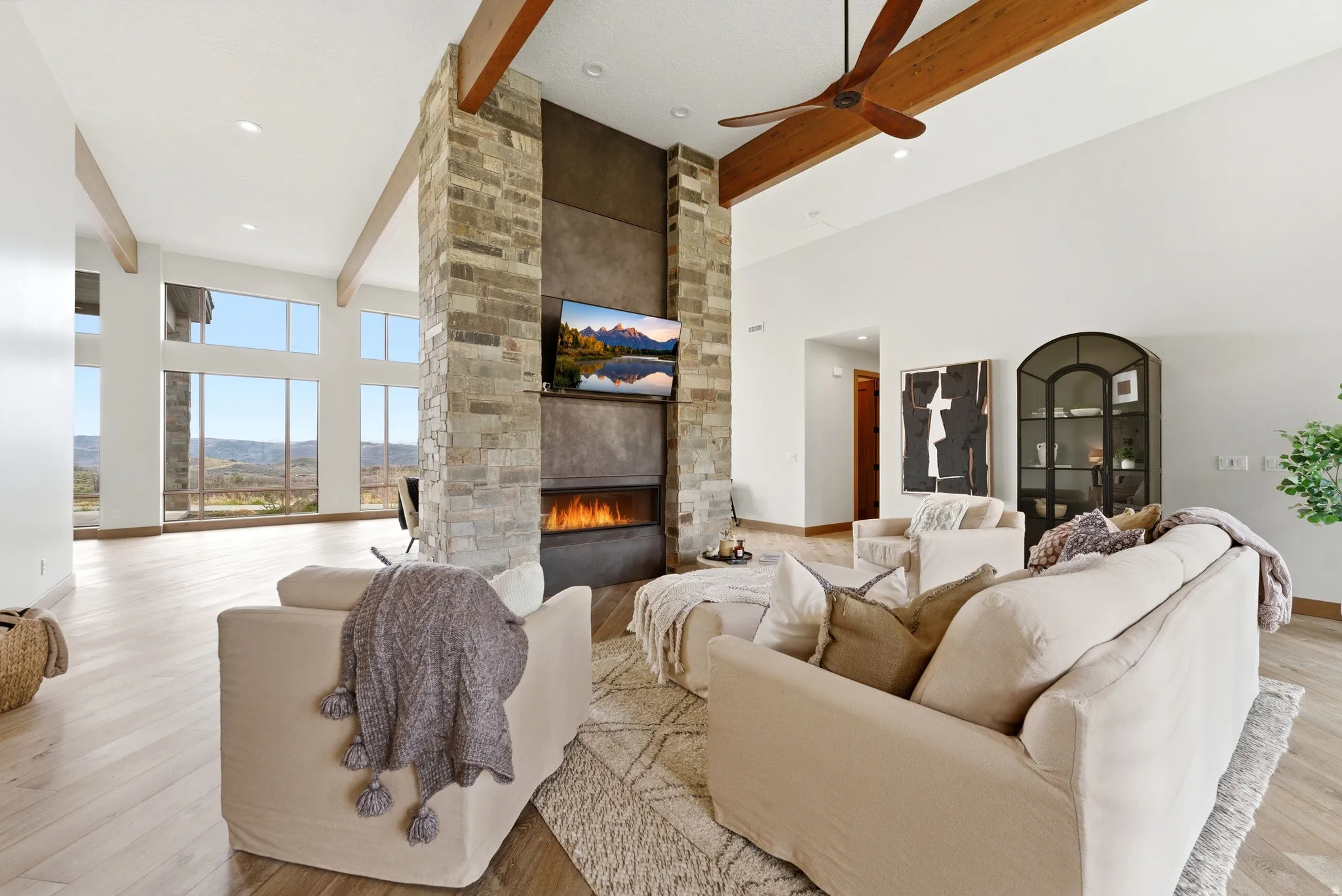 Spacious living area featuring a central stone fireplace, integrated linear fire feature, and wood-finish flooring