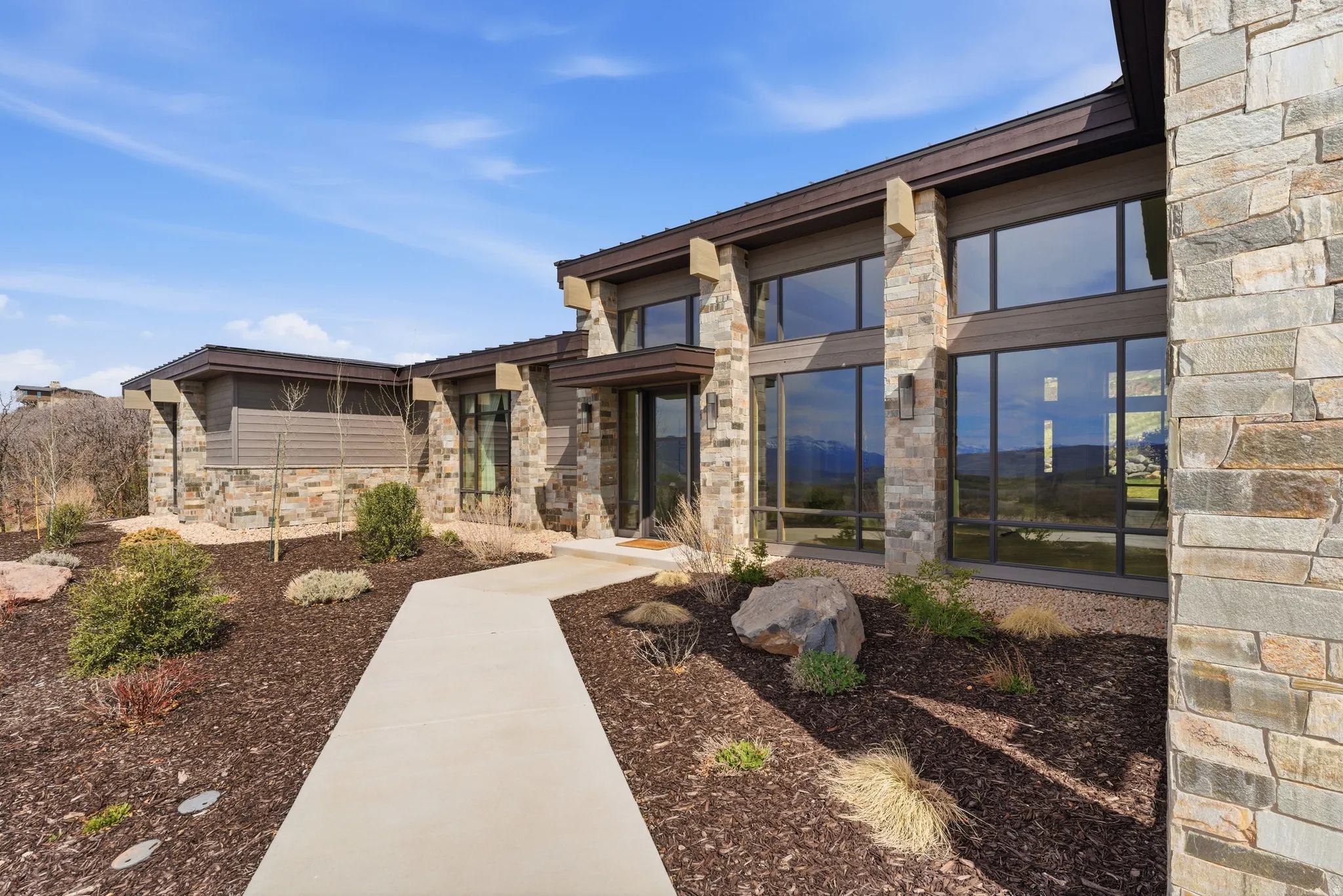 Modern single-story exterior featuring extensive natural stone cladding