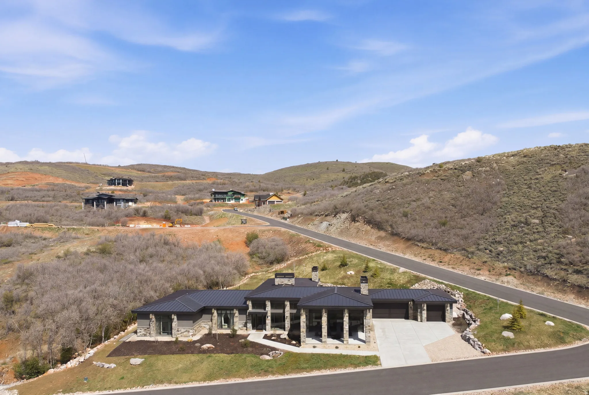 Contemporary ranch-style residence featuring stone and stucco exterior, multiple garages, and a metal roof
