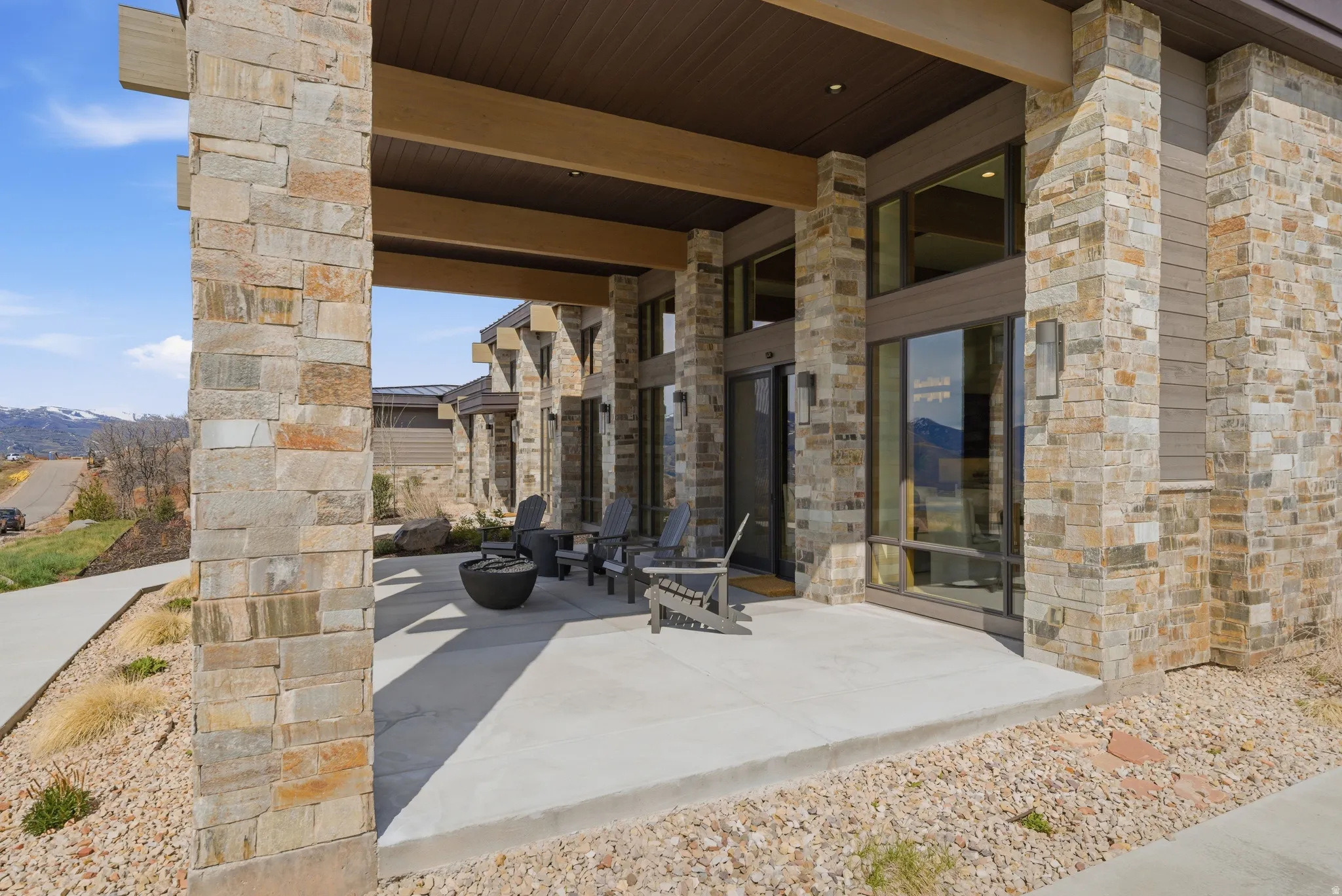 Expansive covered outdoor patio featuring stone columns, a concrete surface, and large format windows