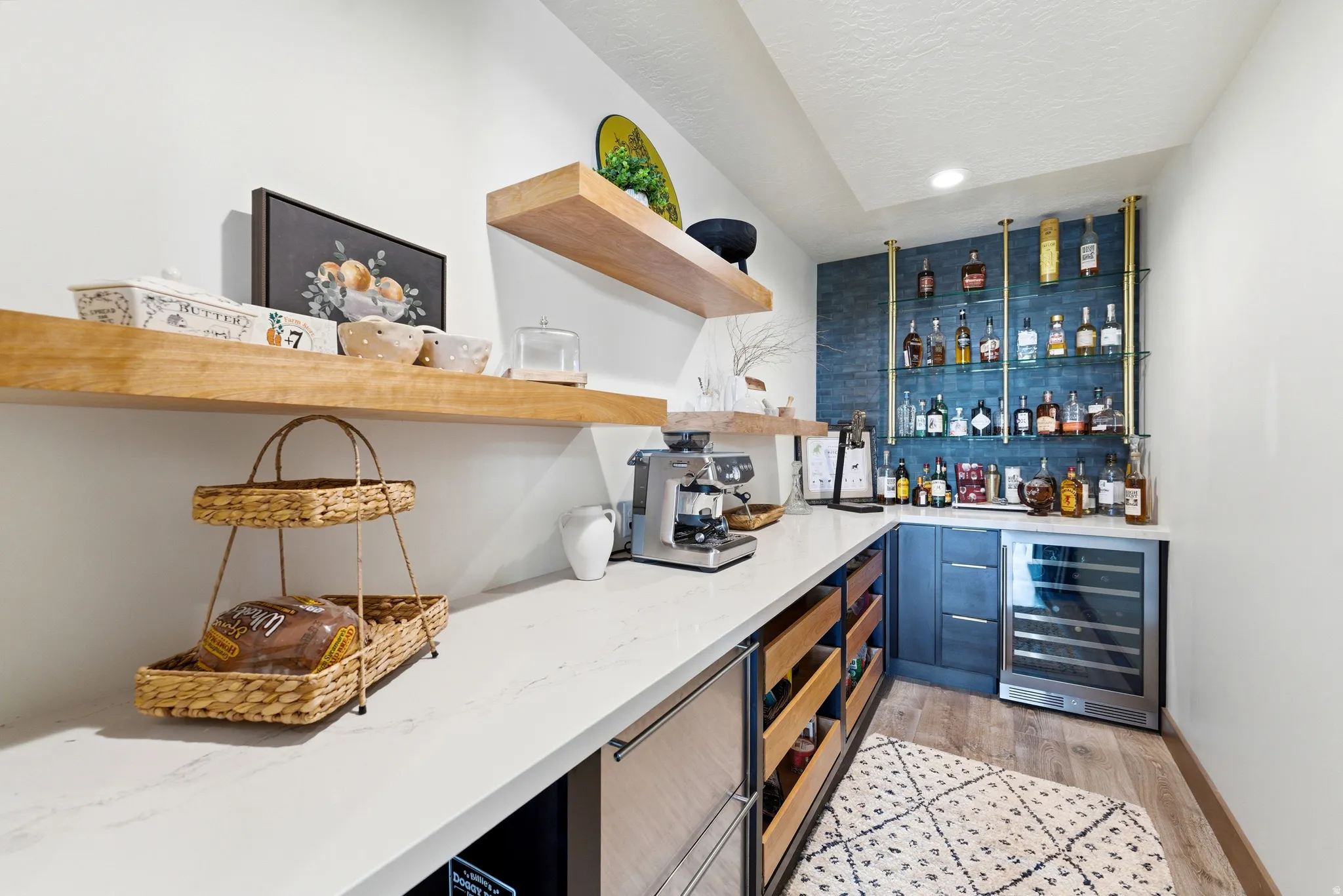 Custom beverage station featuring a built-in wine refrigerator, brass-finished shelving, and a textured blue accent wall