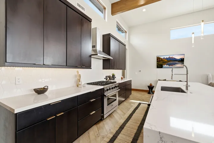 Modern kitchen featuring dark cabinetry, white countertops, and a hexagonal tile backsplash