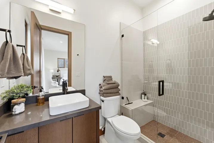 Modern bathroom featuring a glass-enclosed shower with subway tile surround and a built-in bench