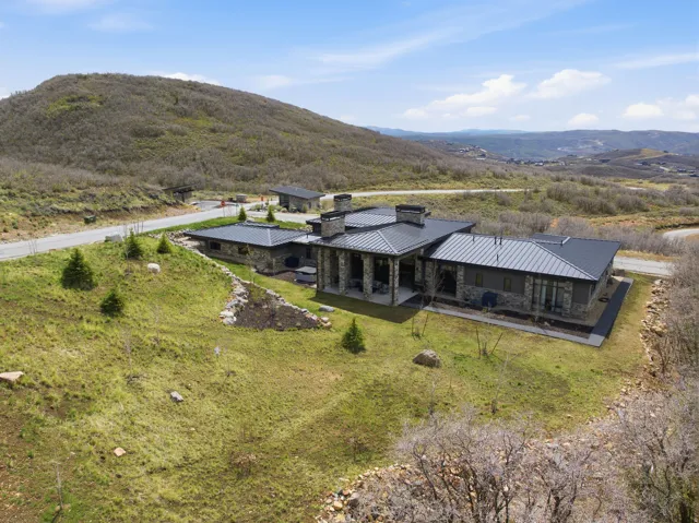 Contemporary residence featuring a stone and siding exterior with a dark metal roof