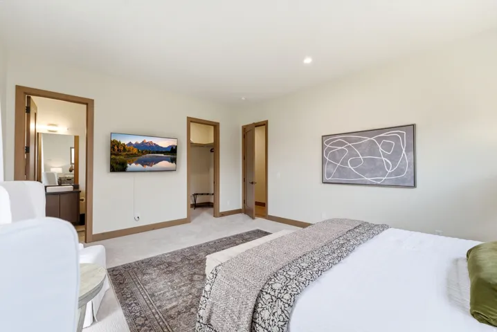 Bright bedroom featuring light wall tones, recessed lighting, and wood-finish trim and doors