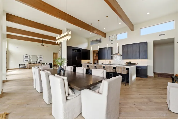 Spacious open-concept interior featuring high vaulted ceilings with exposed wood beams