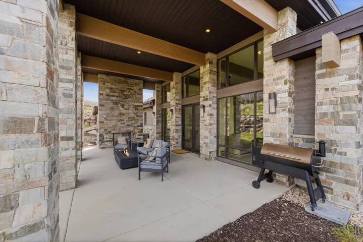 Covered outdoor patio featuring extensive stacked stone masonry and dark wood-finish ceiling details