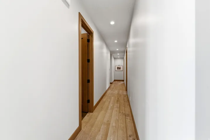 Hallway featuring wood-finish flooring, recessed lighting, and white walls