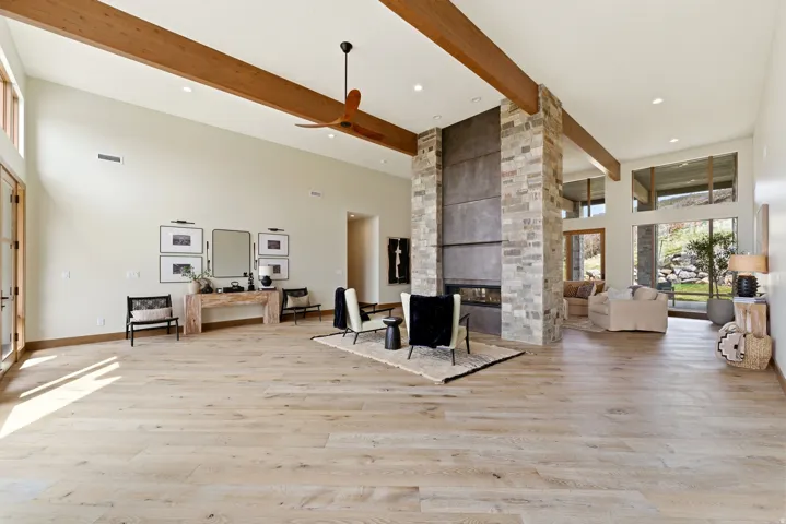 Spacious living area featuring light wood-finish flooring and high ceilings with exposed wood beams