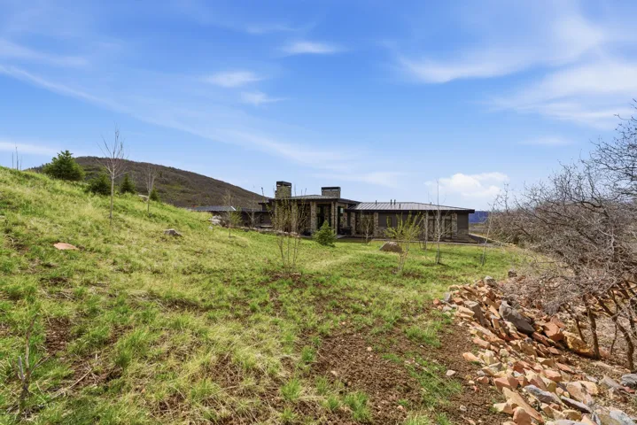 Stone exterior architecture featuring multiple chimneys, a dark roofline, and expansive grounds