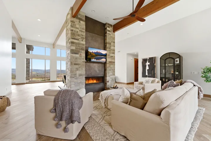 Spacious living area featuring a central stone fireplace, integrated linear fire feature, and wood-finish flooring