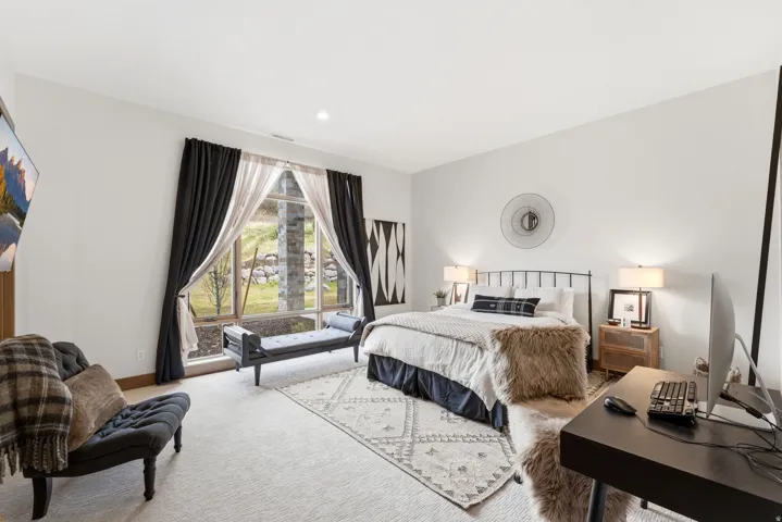 Spacious bedroom featuring large windows, light-toned carpeting, recessed lighting, and a neutral color palette